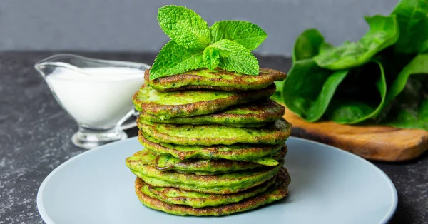 Delicious healthy breakfast with spinach pancakes and yogurt sauce on blak background