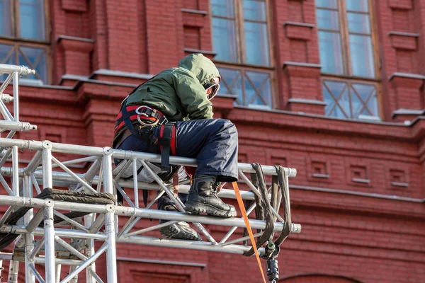 Industrial climber in uniform sitting ts on a building structure