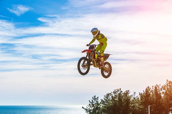 Corredor en una motocicleta en vuelo, salta y despega en un trampolín contra el cielo . —  Fotos de Stock