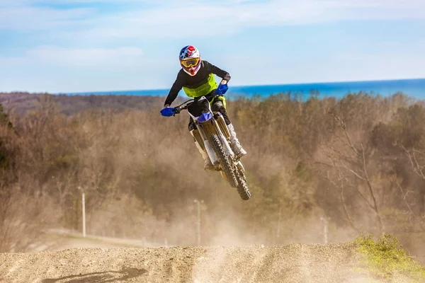 Pilota su una moto in volo, salta e decolla su un trampolino di lancio contro il cielo . — Foto Stock