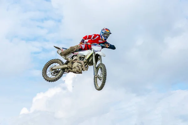 Racer on a motorcycle in flight, jumps and takes off on a springboard against the sky. — Stock Photo, Image