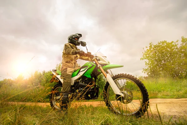 Hombre con casco de moto y uniforme de seguridad sentado en un gr —  Fotos de Stock