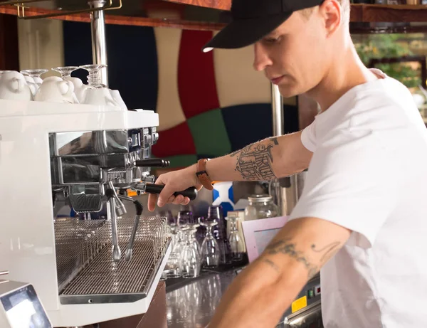 Молодий татуйований бариста в кав'ярні робить каву за допомогою ком — стокове фото