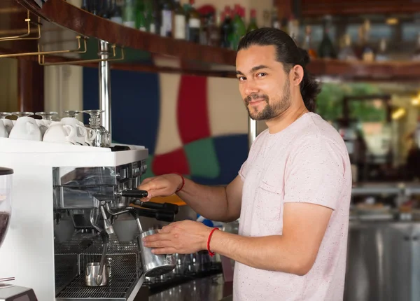 Красивий молодий усміхнений чоловік бариста готує кавовий напій, використовуючи — стокове фото