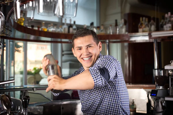 Щасливий усміхнений бармен потискає коктейль у сталевому шейкері . — стокове фото