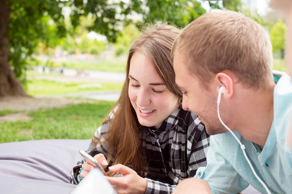 Happy smiling couple hanging out outdoors, laying on a cushion a