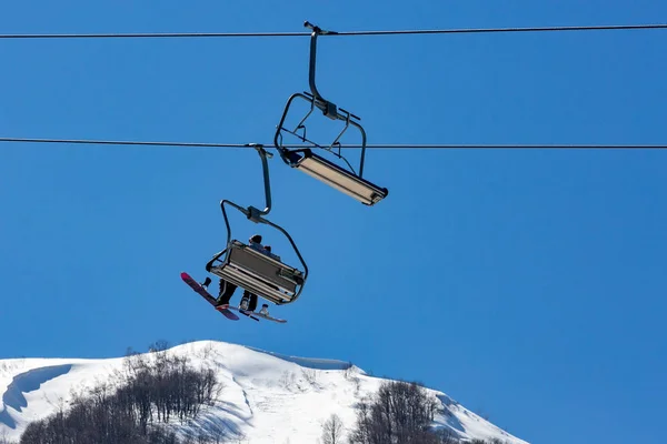 Ski lift with seats going over the mountain and paths from skies and snowboards — Stock Photo, Image