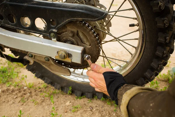 Hombre pernos de ajuste con llave de zócalo en la rueda trasera de la motocicleta . —  Fotos de Stock