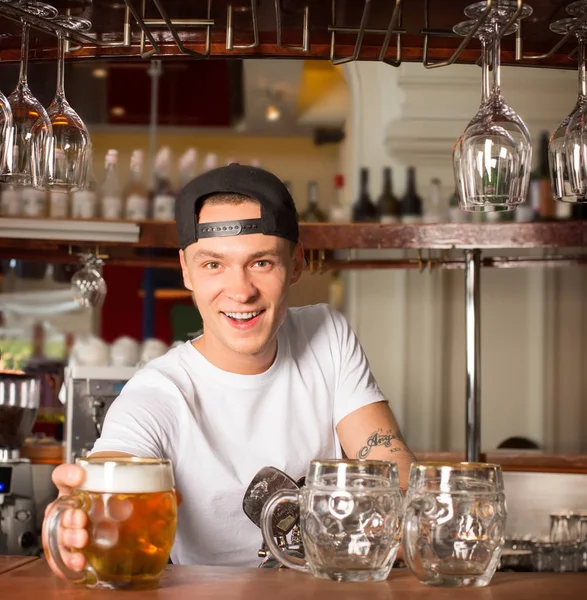 Молодий веселий щасливий бармен пропонує пиво клієнту . — стокове фото