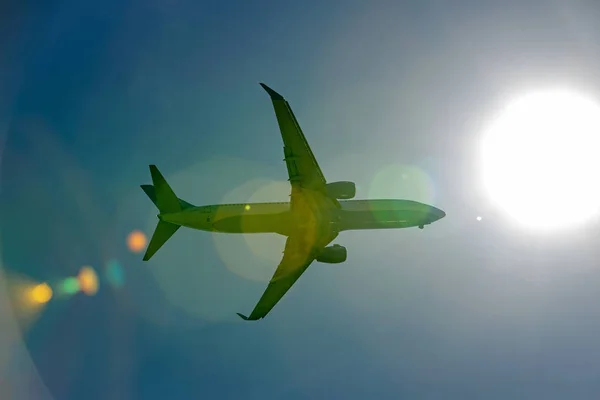 日光光線の青い空を飛んでいる旅客機 — ストック写真