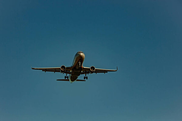Large passenger plane flying in the blue sky in sunlight rays
