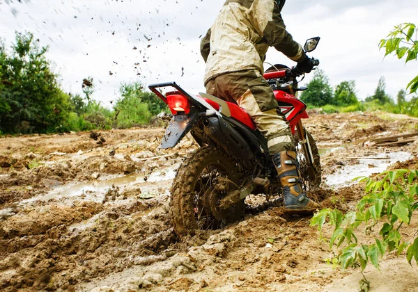 The man on a motorcycle rides through the mud