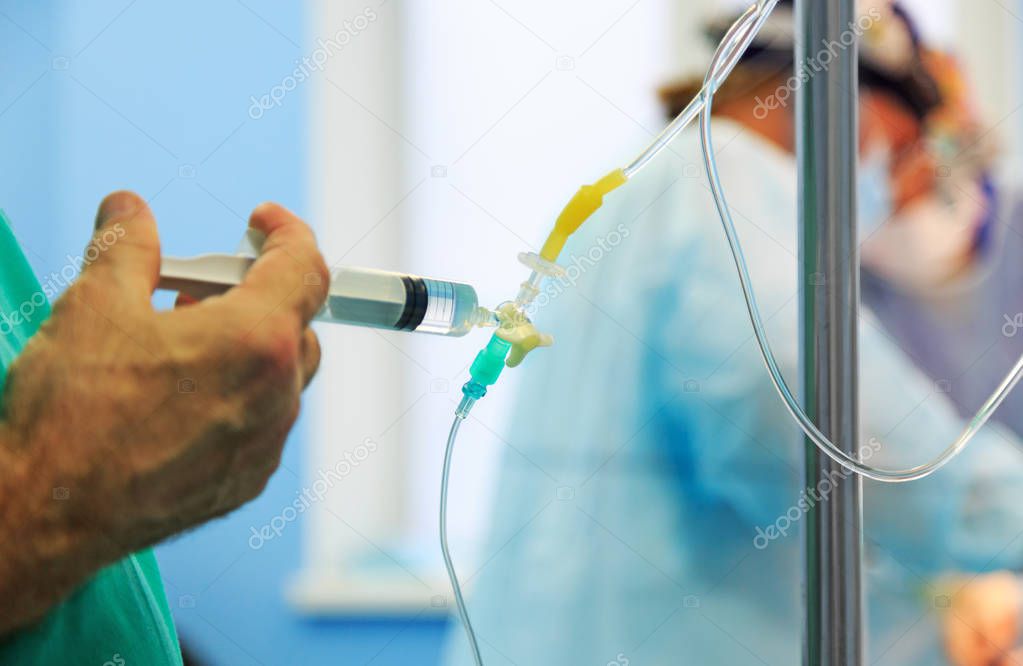 Doctors hand and infusion drip in hospital on blurred backgroun