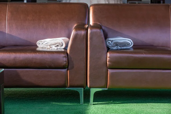 Sofá salón moderno y elegante de cuero marrón con manta de lana en el brazo . — Foto de Stock