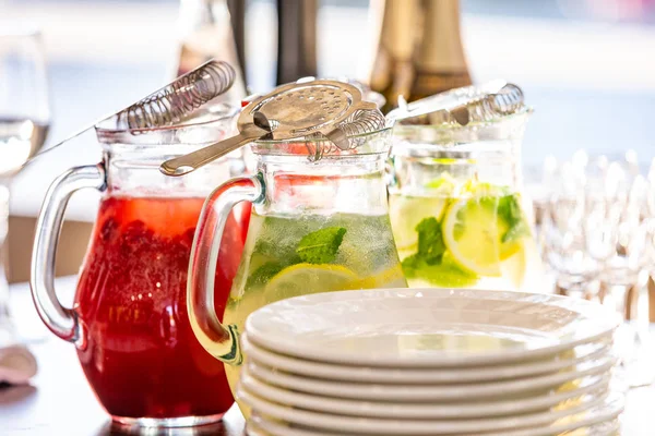 Dois jarros de vidro de limonada de framboesa fresca caseira ou coquetel de mojito virgem com uma palha na mesa entre os pratos preparados para servir — Fotografia de Stock