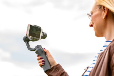 the girl with the phone on the stabilizer leads the videoblog. She takes himself to the camera Smartphone clipart