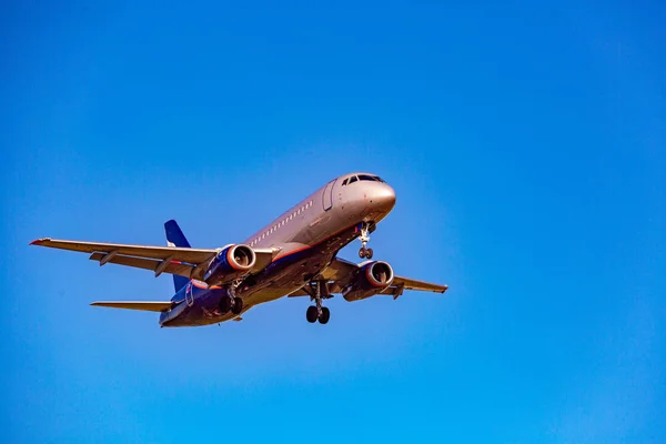 Passagiersvliegtuig vliegen in de blauwe hemel in zonlicht stralen — Stockfoto