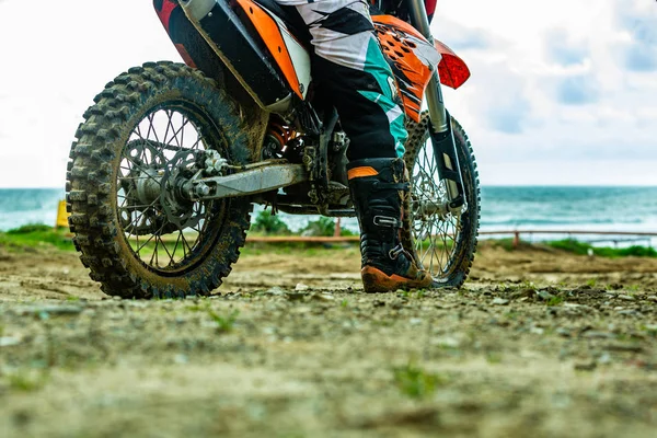 Pengendara sepeda motor dalam pakaian pelindung duduk di atas sepeda motor di depan laut — Stok Foto