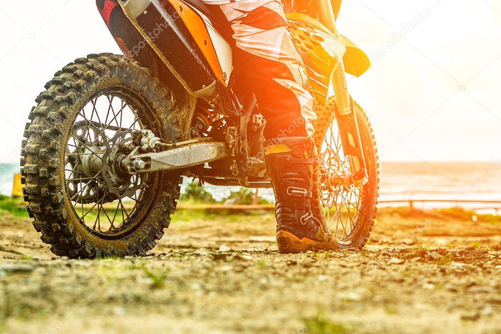 Motorcyclist in a protective suit sitting on motorbike in front of the sea