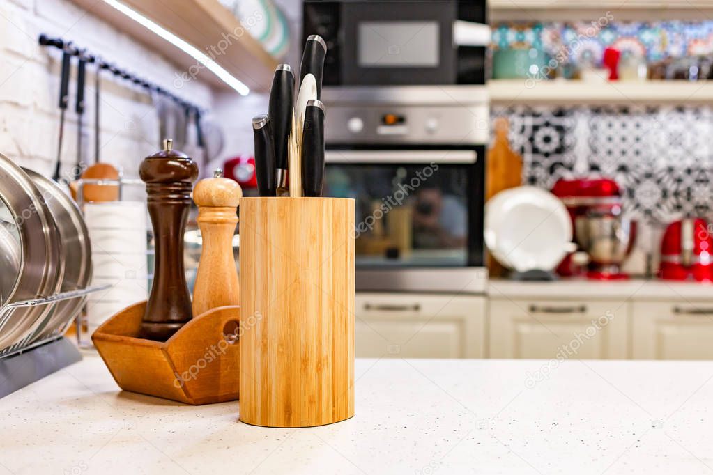Kitchen knives in a special wooden stand with spice jars. Close-up. Kitchen concept