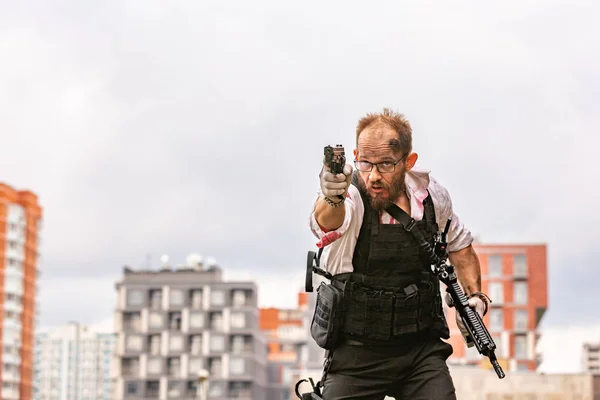 Man gekleed in een kogelvrij vest, een shirt in zijn bloed, streeft naar een slachtoffer met een pistool actie filmstijl — Stockfoto
