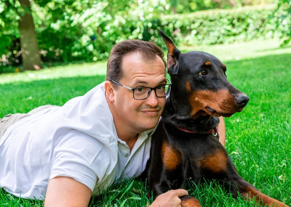 Man plays in the park with Dobermann — Stock Photo, Image
