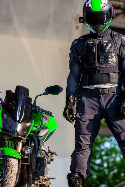 Pengendara sepeda motor dengan helm dan mengenakan pakaian pelindung berdiri di bawah jembatan — Stok Foto