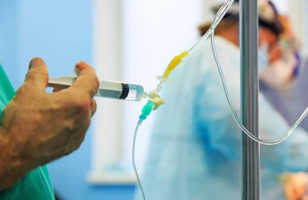 Doctors hand and infusion drip in hospital on blurred backgroun — Stock Photo, Image