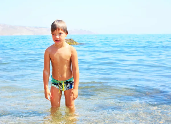 Cheerful llittle boy enjoy play with water on beach. — Stock Photo, Image