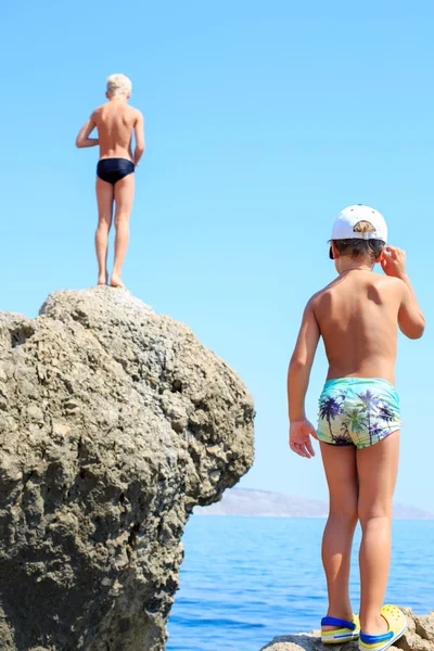 Dos chicos nadando de pie en una playa pedregosa a diferente altura —  Fotos de Stock