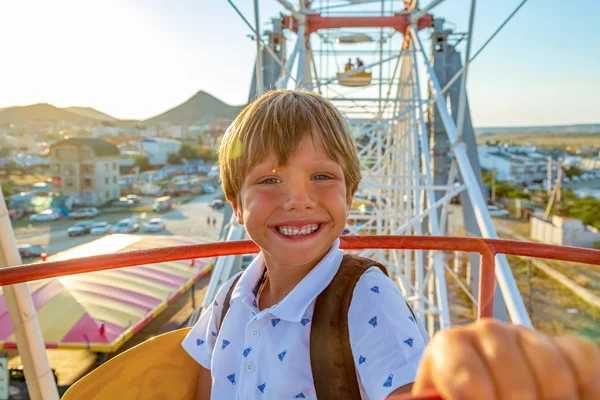 Smilling opgewonden jongen genieten van het uitzicht vanuit het reuzenrad in attractiepark — Stockfoto