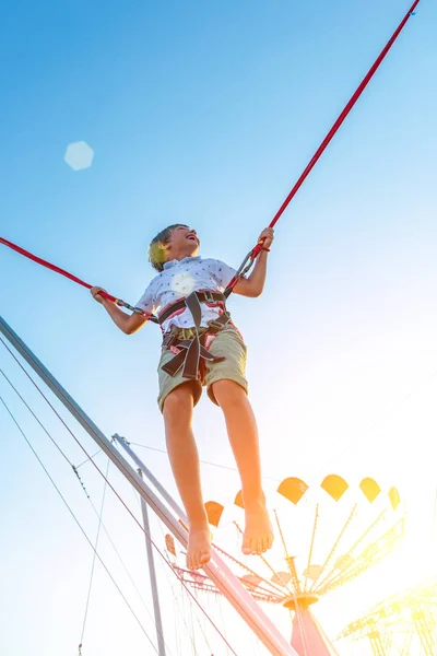 Opgewonden jongen smilling springen op een trampoline met verzekering. — Stockfoto