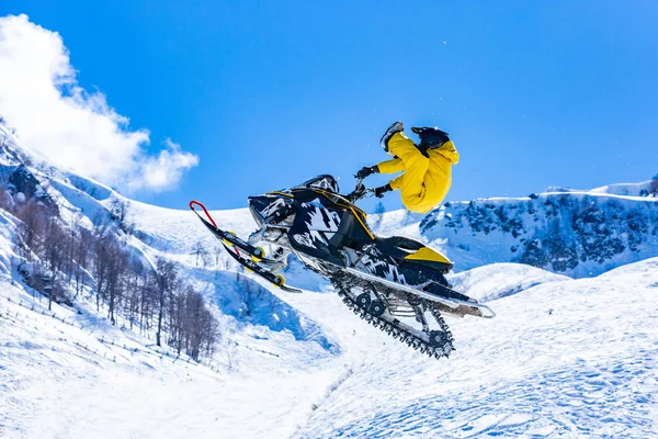 Racer na śniegu kot w locie, skacze i startuje na springboard przeciwko snowy góry — Zdjęcie stockowe