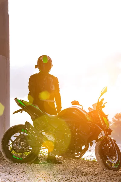 Motociclista en un casco y en un traje de protección se encuentra debajo del puente —  Fotos de Stock