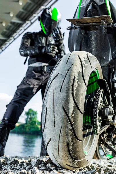 Motorcyclist stop under the bridge over the road waiting for rain to stop