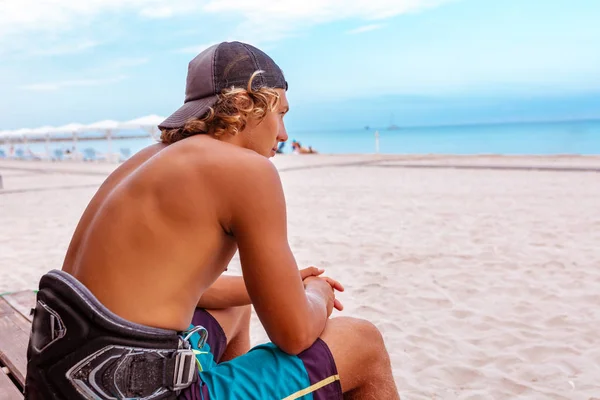 Η surfer κάθεται με την πλάτη στην κάμερα στη βεράντα στην παραλία κοιτάζοντας την απόσταση, — Φωτογραφία Αρχείου