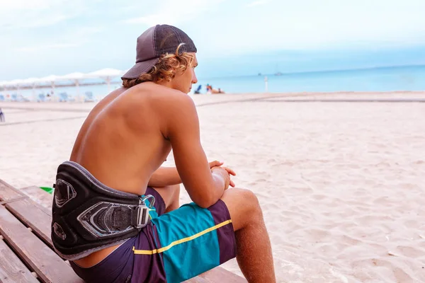 Η surfer κάθεται με την πλάτη στην κάμερα στη βεράντα στην παραλία κοιτάζοντας την απόσταση, — Φωτογραφία Αρχείου