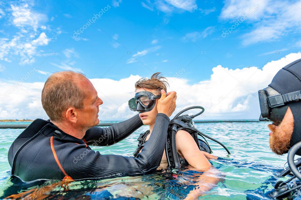 a man in a suit for diving prepares a boy to dive