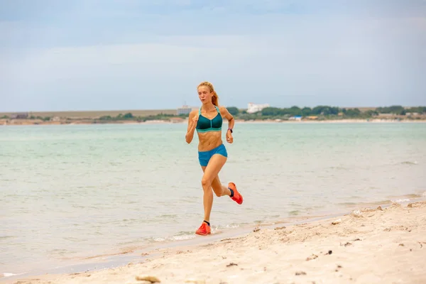 Όμορφη αθλητική γυναίκα που τρέχει κατά μήκος την πανέμορφη αμμώδη παραλία, υγιεινό τρόπο ζωής, απολαμβάνοντας δραστήριες καλοκαιρινές διακοπές κοντά στη θάλασσα — Φωτογραφία Αρχείου