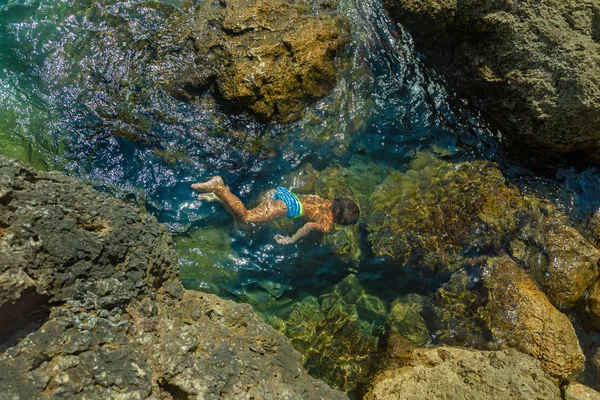 Pojke som simmar under vattnet, vacker utsikt över kristall klart genomskinliga vattnet i havet — Stockfoto