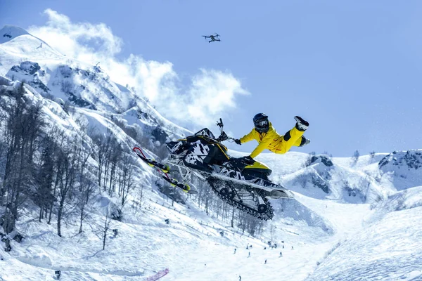 Racer on a snow-cat in flight, jumps and takes off on a springboard against the snowy mountains — Stock Photo, Image