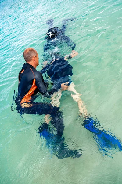 Dalış için takım elbiseli bir adam dalış için bir çocuk hazırlar — Stok fotoğraf