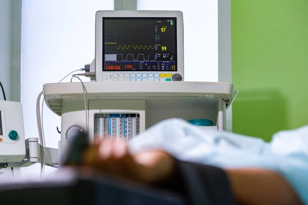 Patients hand with a sensor on the blurry background of the group of doctors in the operating room. Close up, Selective focus — Stock Photo, Image