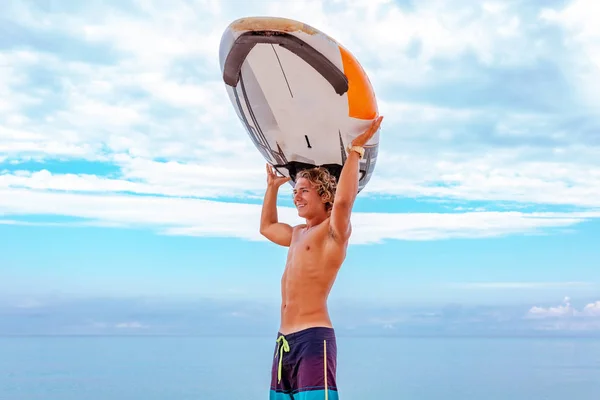 Stilig man vandra med vit blank surfing board vänta för våg att surfa plats på havet stranden. Begreppet sport, fitness, frihet, lycka, nya moderna livet, hipster. — Stockfoto