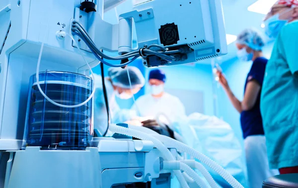 Fragment van ademhalingsapparatuur in de operatiekamer, onscherpe achtergrond met team chirurg op het werk in het ziekenhuis tijdens hun werk. — Stockfoto