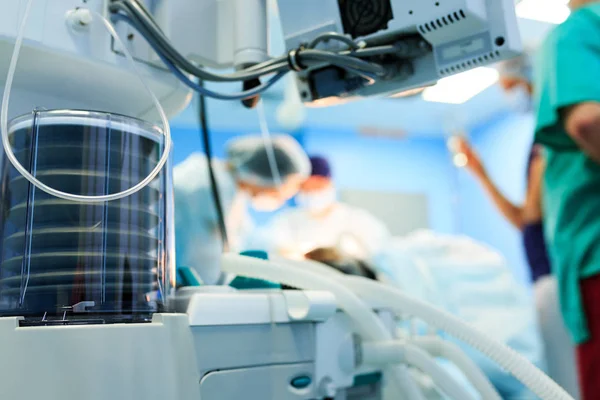 Fragment of breathing apparatus in the operating room, blurred background with team surgeon at work in hospital during their work. — Stock Photo, Image