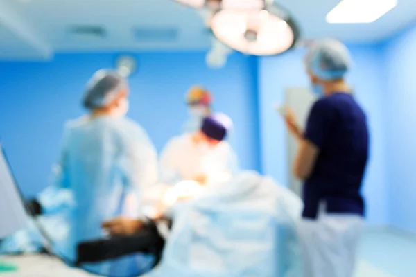 Surgery, medicine and people concept - Blurred background with surgeons in operating room at hospital during their work. — Stock Photo, Image