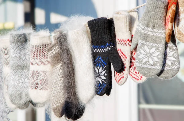 Kesztyű a téli karácsonyi piacon. Egy változatos színes kötött gyapjú kesztyű lóg egy kötélen. Karácsonyi ajándék vagy ajándék. — Stock Fotó