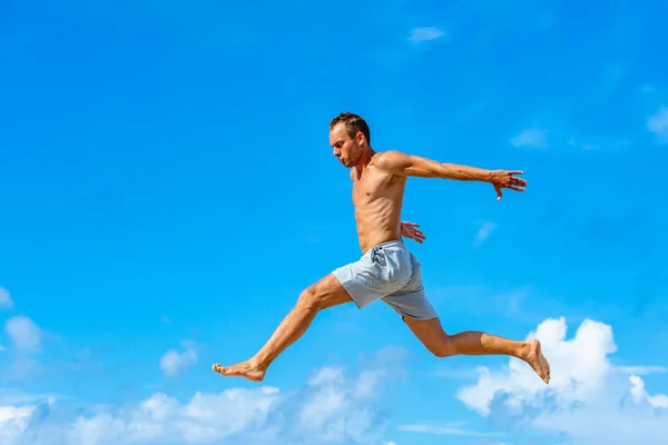 Joven haciendo salto de parkour en el fondo del cielo azul en el soleado día de verano — Foto de Stock