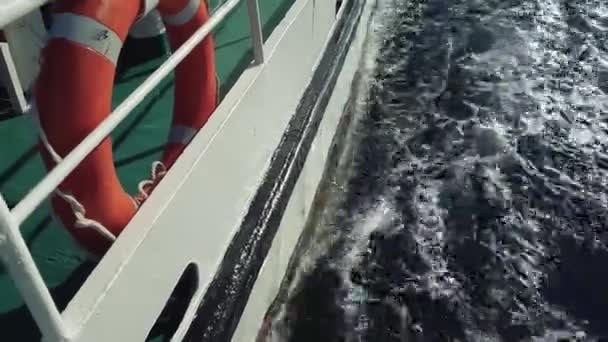 Barco con una boya salvavidas a bordo se mueve en los mares olas. las olas divergen del barco — Vídeo de stock